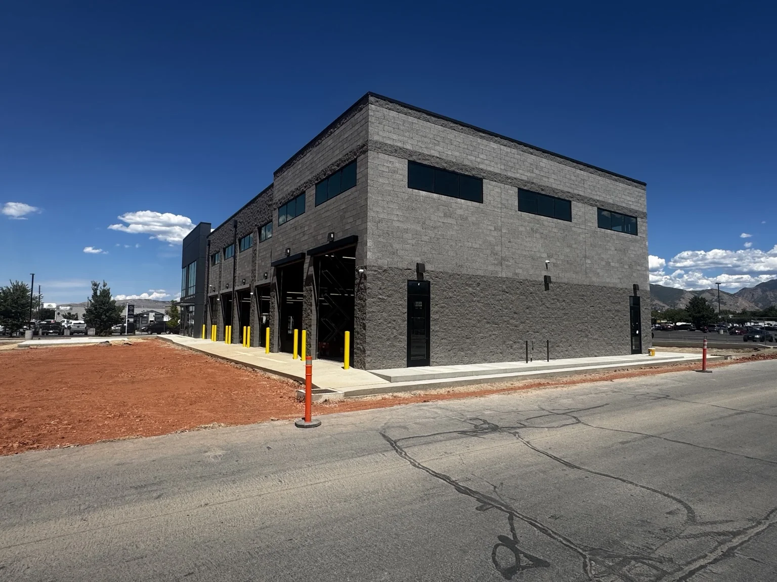 Exterior corner of the Big O Tire facility with painted service bays, dark trim, and yellow safety bollards