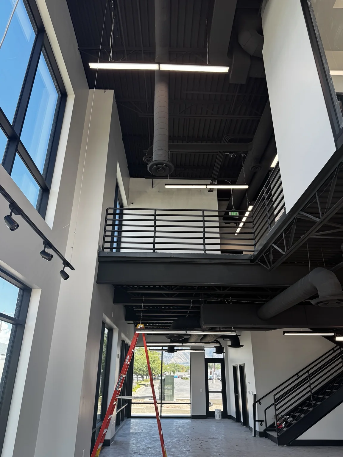 Double-height Big O Tire showroom with a painted black ceiling, mezzanine, and dark steel railings