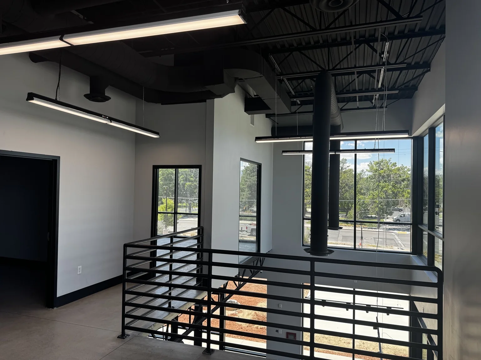 Big O Tire showroom mezzanine overlooking the double-height lobby with black architectural railings and exposed ceiling