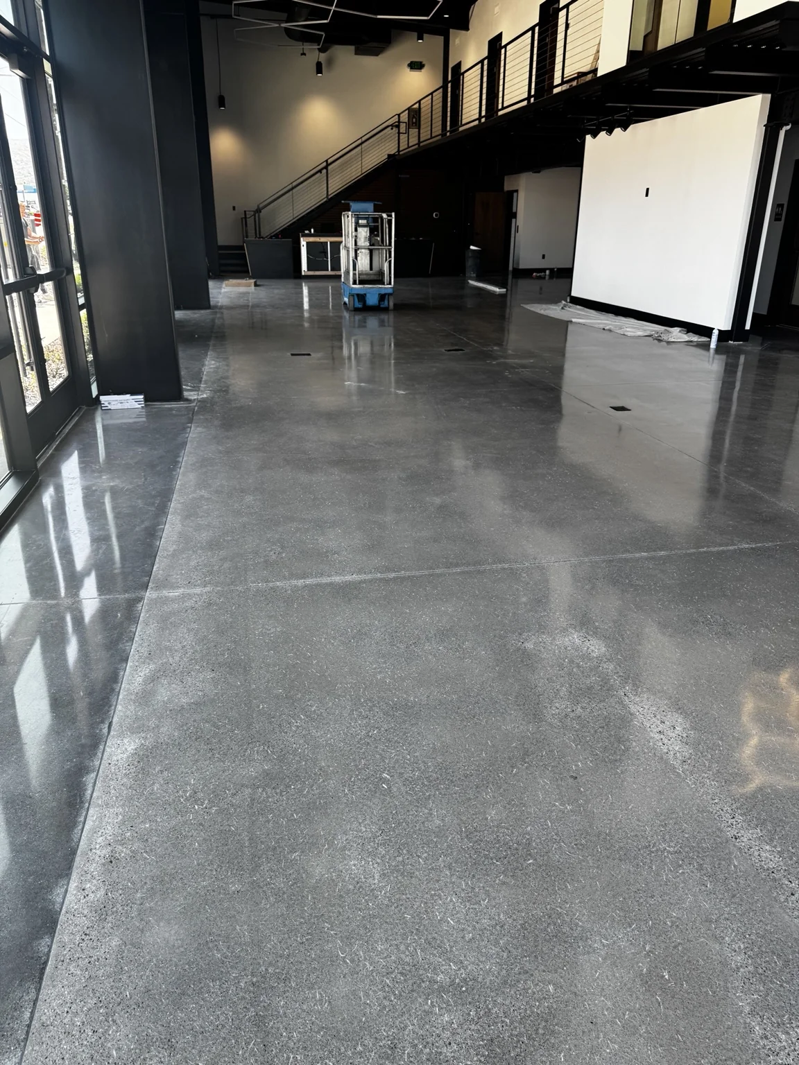 Close view across the boat-shop polished concrete floor toward the black steel mezzanine