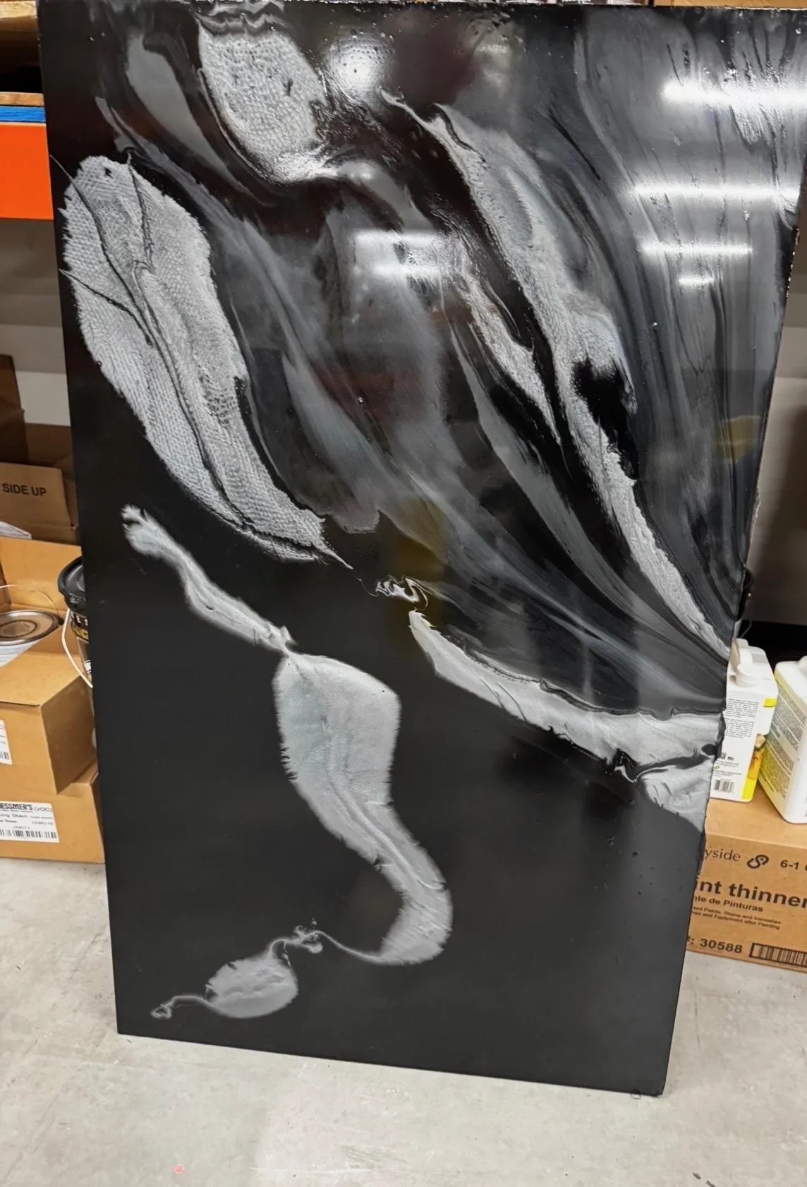 Glossy black metallic epoxy sample with flowing silver and white marble-like pigment effects