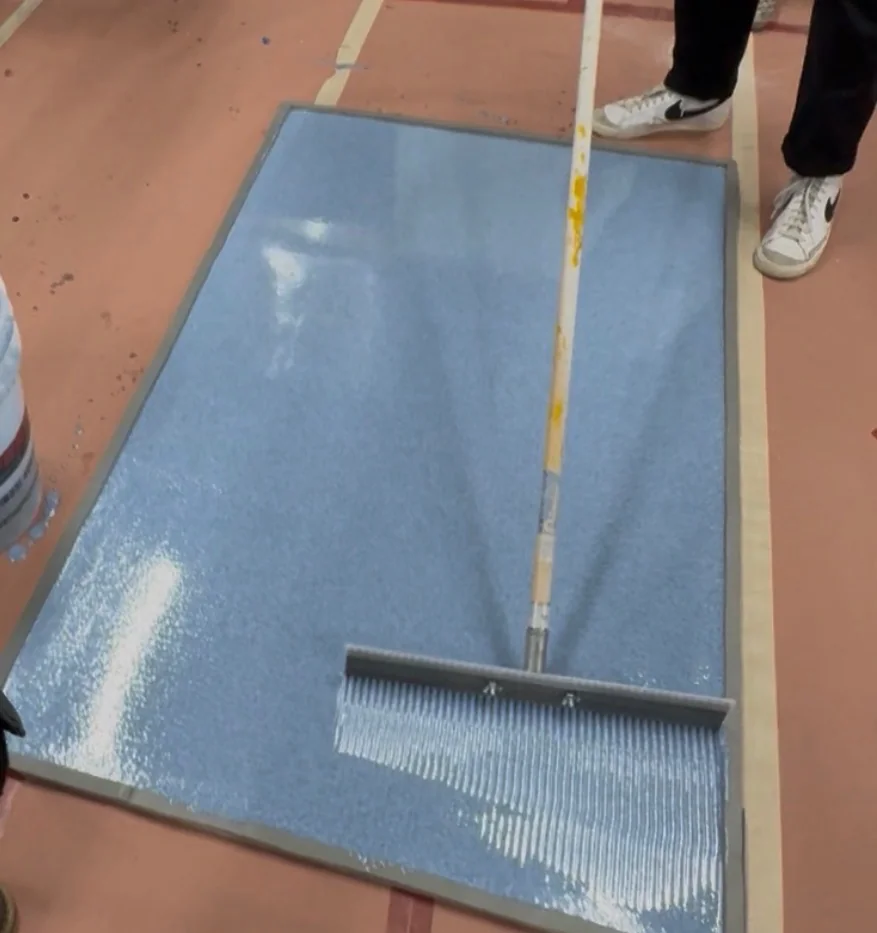 Blue metallic epoxy being spread smoothly over a sample panel during the professional coating application process